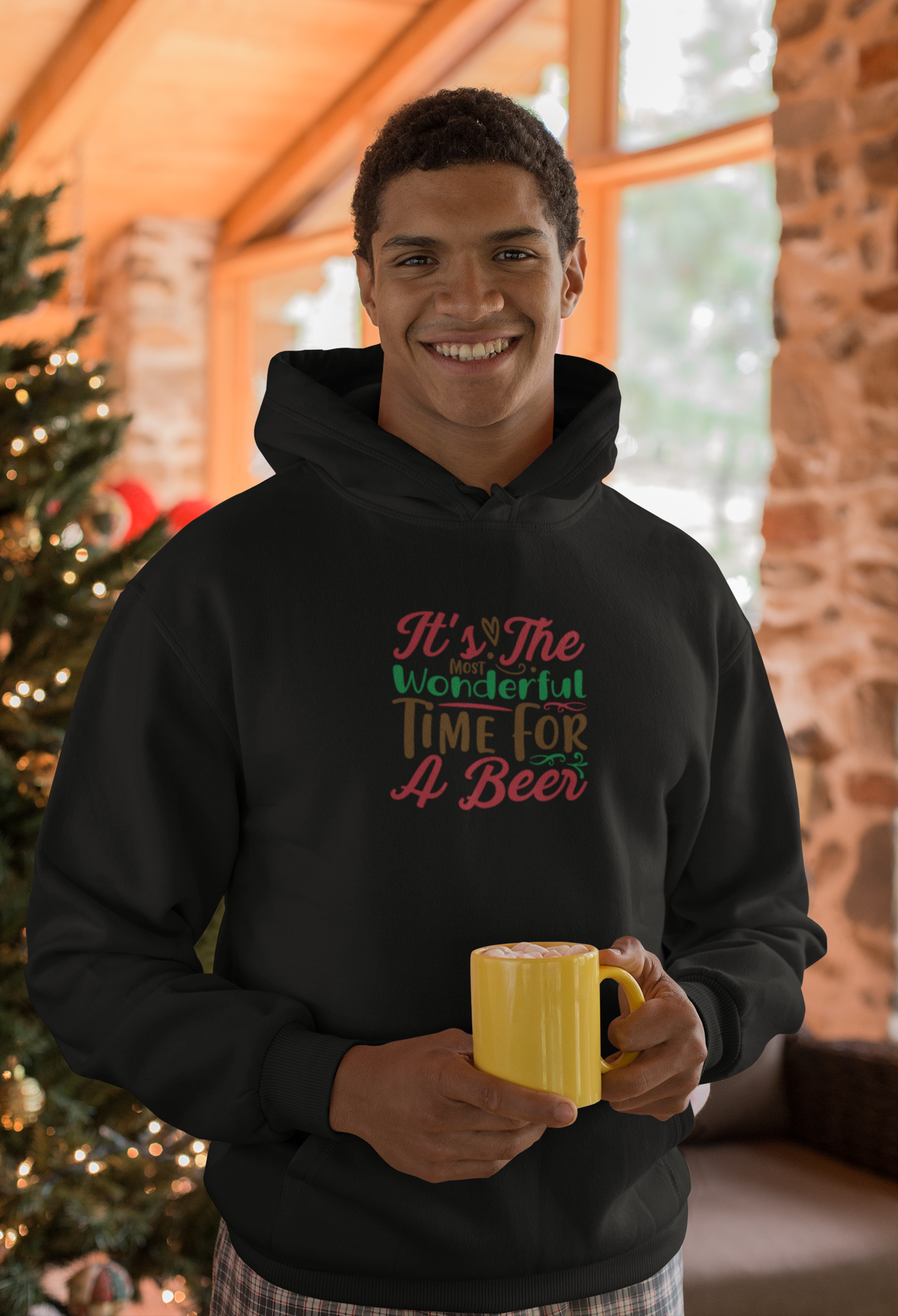 Man by a Christmas tree wearing the Most Wonderful Time for a Beer black hoodie